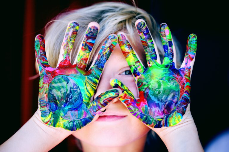 child holding hands covered in paint over face